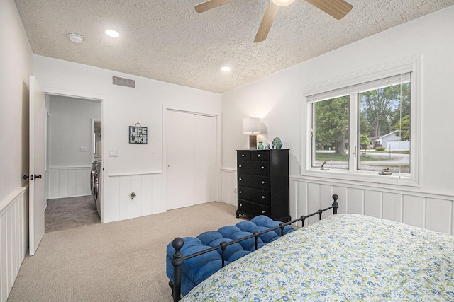 8994 Lenhards Lndg, Clarksville, MI 48815 - bedroom with stacked washer / dryer, a textured ceiling, a wainscoted wall, carpet flooring, and a decorative wall