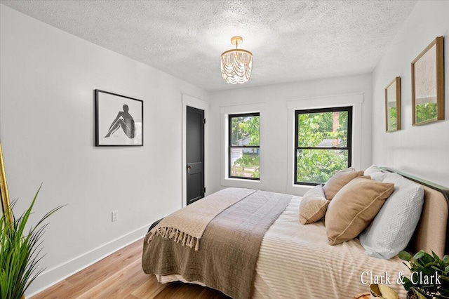 820 Hackett St, Ionia, MI 48846 - bedroom featuring wood finished floors, a chandelier, baseboards, and a textured ceiling