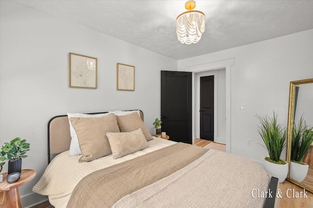 820 Hackett St, Ionia, MI 48846 - bedroom with light wood-style floors, a chandelier, and a textured ceiling
