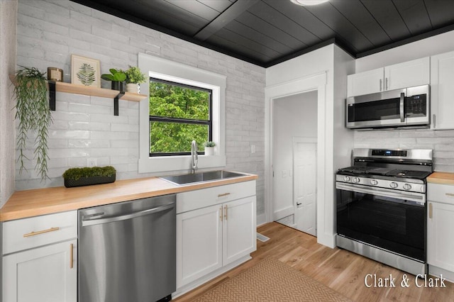 820 Hackett St, Ionia, MI 48846 - kitchen with appliances with stainless steel finishes, a sink, decorative backsplash, light wood finished floors, and white cabinets