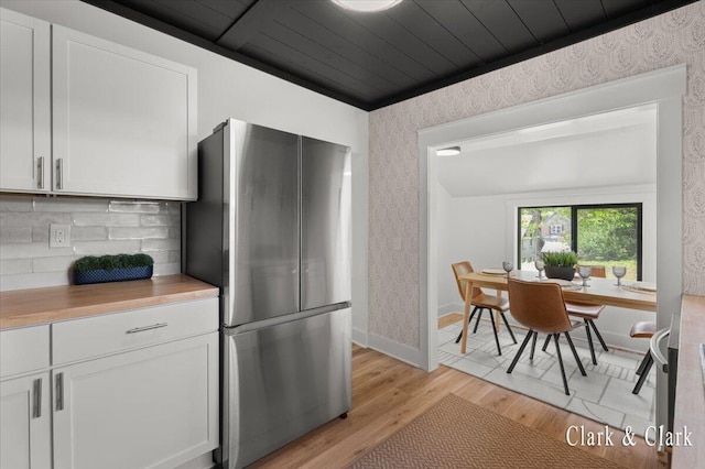 820 Hackett St, Ionia, MI 48846 - kitchen featuring freestanding refrigerator, wallpapered walls, white cabinetry, light wood-type flooring, and backsplash