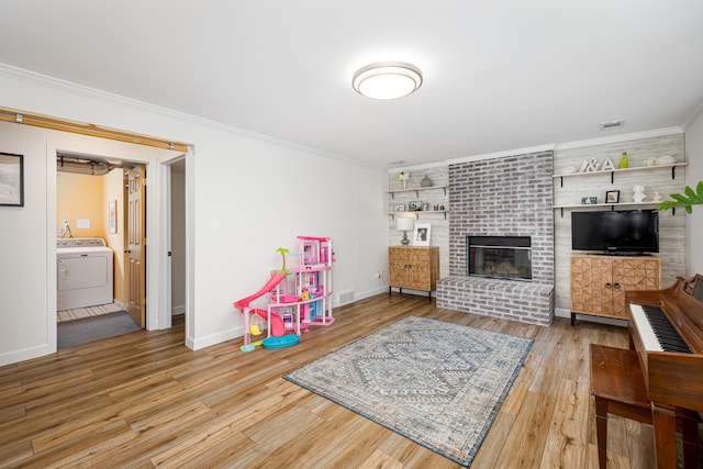 9177 Horseshoe Bnd, Dexter, MI 48130 - playroom featuring washer / clothes dryer, wood finished floors, baseboards, a brick fireplace, and ornamental molding