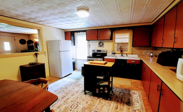 8424 3rd St, Onekama, MI 49675 - kitchen with freestanding refrigerator, stainless steel range with electric stovetop, light countertops, backsplash, and an ornate ceiling