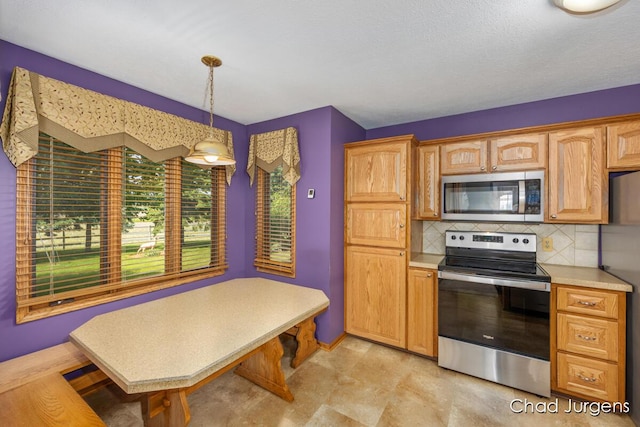 7564 Quincy St, Zeeland, MI 49464 - kitchen featuring appliances with stainless steel finishes, decorative backsplash, light countertops, and hanging light fixtures
