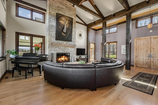 10258 Burgoyne Rd, Berrien Springs, MI 49103 - living area featuring high vaulted ceiling, a stone fireplace, beamed ceiling, healthy amount of natural light, and light wood-style flooring