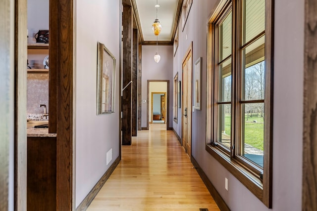 10258 Burgoyne Rd, Berrien Springs, MI 49103 - corridor featuring plenty of natural light, light wood finished floors, baseboards, ornamental molding, and attic access