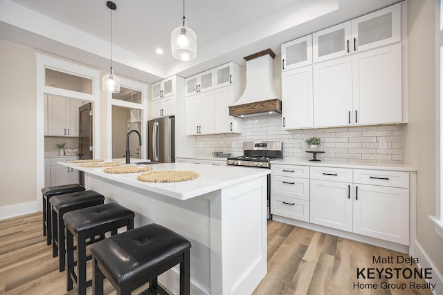 11012 Riverview Dr, Big Rapids, MI 49307 - kitchen with custom range hood, appliances with stainless steel finishes, backsplash, light countertops, and a kitchen breakfast bar