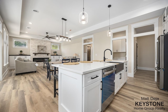 11012 Riverview Dr, Big Rapids, MI 49307 - kitchen featuring appliances with stainless steel finishes, a raised ceiling, ceiling fan, a breakfast bar area, and a fireplace