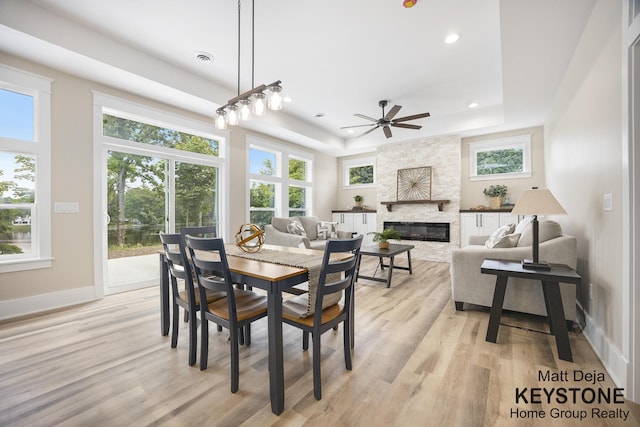 11012 Riverview Dr, Big Rapids, MI 49307 - dining space featuring a tray ceiling, light wood-type flooring, a fireplace, recessed lighting, and ceiling fan