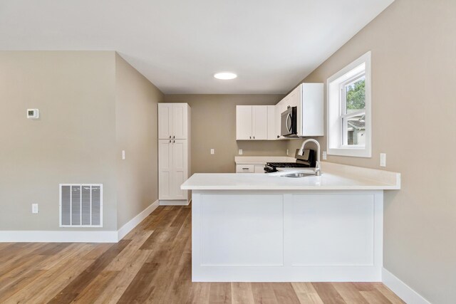307 N Perrine St, Jackson, MI 49201 - kitchen with stainless steel microwave, range, white cabinets, and light countertops