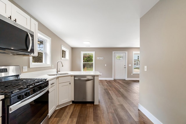 307 N Perrine St, Jackson, MI 49201 - kitchen featuring appliances with stainless steel finishes, dark wood finished floors, a peninsula, and white cabinetry