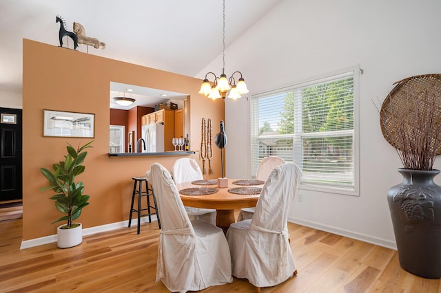 15532 Winchester Cir, Grand Haven, MI 49417 - dining room featuring light wood finished floors, a chandelier, baseboards, and high vaulted ceiling