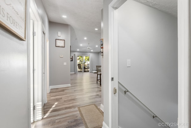 2883 Harmony Ct, Wyoming, MI 49519 - hallway with an upstairs landing, a textured ceiling, light wood finished floors, recessed lighting, and baseboards