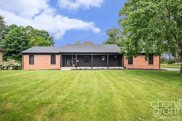 1757 Westlane Dr NE, Grand Rapids, MI 49505 - rear view of house featuring brick siding, a lawn, a sunroom, and a chimney