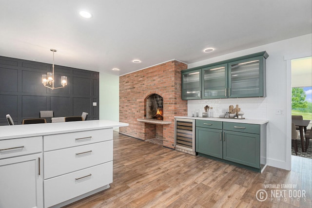 1757 Westlane Dr NE, Grand Rapids, MI 49505 - kitchen with wine cooler, green cabinetry, a chandelier, light countertops, and light wood-style floors