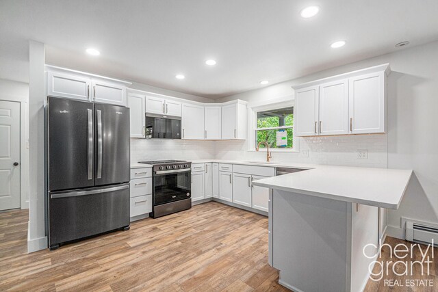 1757 Westlane Dr NE, Grand Rapids, MI 49505 - kitchen with stainless steel appliances, a peninsula, a baseboard radiator, backsplash, and white cabinetry