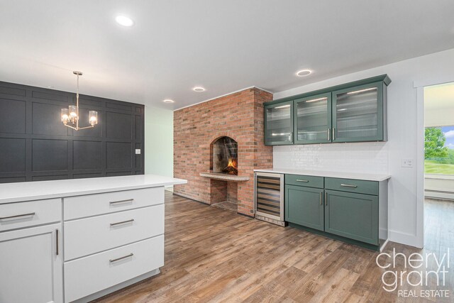 1757 Westlane Dr NE, Grand Rapids, MI 49505 - kitchen with beverage cooler, green cabinetry, light countertops, light wood finished floors, and a chandelier