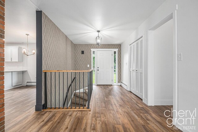 1757 Westlane Dr NE, Grand Rapids, MI 49505 - foyer entrance with a chandelier, wood finished floors, a baseboard radiator, and wallpapered walls