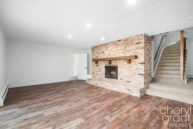 1757 Westlane Dr NE, Grand Rapids, MI 49505 - unfurnished living room with wood finished floors, recessed lighting, stairway, a fireplace, and a baseboard heating unit