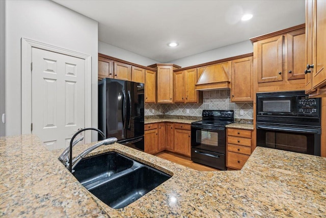 3667 Bay Harbor Dr, Brighton, MI 48114 - kitchen with black appliances, custom range hood, light stone countertops, tasteful backsplash, and brown cabinetry