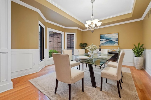 3667 Bay Harbor Dr, Brighton, MI 48114 - dining space featuring a raised ceiling, a chandelier, light wood finished floors, wainscoting, and ornamental molding