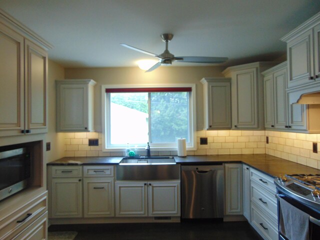 10114 Lincoln Dr, Huntington Woods, MI 48070 - kitchen featuring stainless steel appliances, a sink, ceiling fan, dark countertops, and tasteful backsplash