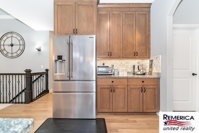 52951 Royal Park Ave, Utica, MI 48315 - kitchen featuring stainless steel fridge with ice dispenser, light wood-style flooring, arched walkways, and tasteful backsplash