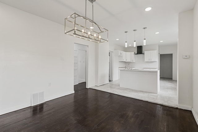 3008 Lothrop St, Detroit, MI 48206 - kitchen featuring wall chimney exhaust hood, light wood finished floors, white cabinets, recessed lighting, and hanging light fixtures