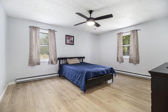 6236 Arbutus, Idlewild, MI 49642 - bedroom featuring a baseboard heating unit, light wood-style floors, a textured ceiling, and ceiling fan