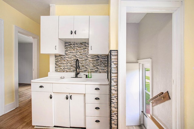 255 E Corey St, Bronson, MI 49028 - kitchen featuring decorative backsplash, light countertops, white cabinetry, a sink, and light wood-style flooring