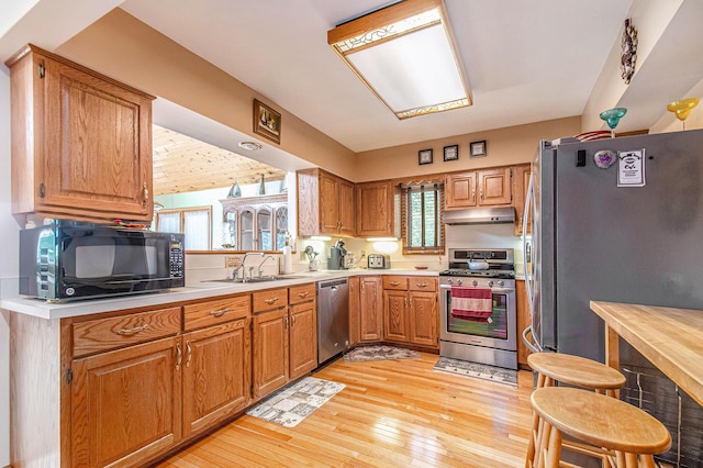 50041 David Dr, Dowagiac, MI 49047 - kitchen with appliances with stainless steel finishes, under cabinet range hood, light countertops, light wood-style floors, and brown cabinetry