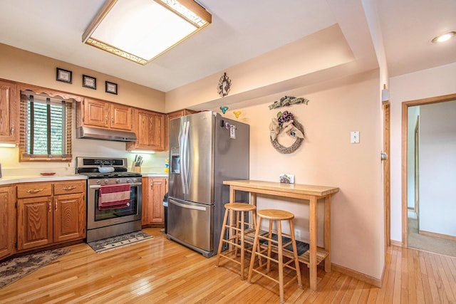 50041 David Dr, Dowagiac, MI 49047 - kitchen with stainless steel appliances, under cabinet range hood, light wood finished floors, light countertops, and brown cabinetry