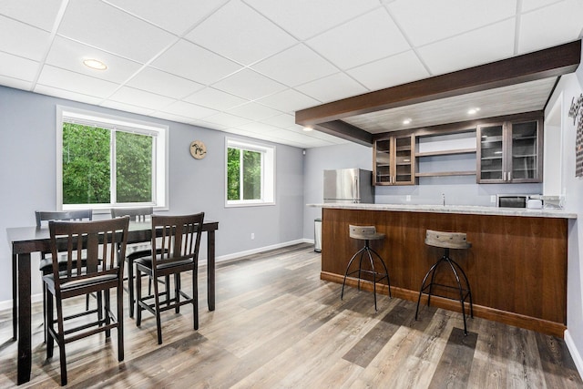 3935 Riley Rdg, Portage, MI 49024 - kitchen with open shelves, glass insert cabinets, wood finished floors, a breakfast bar, and freestanding refrigerator