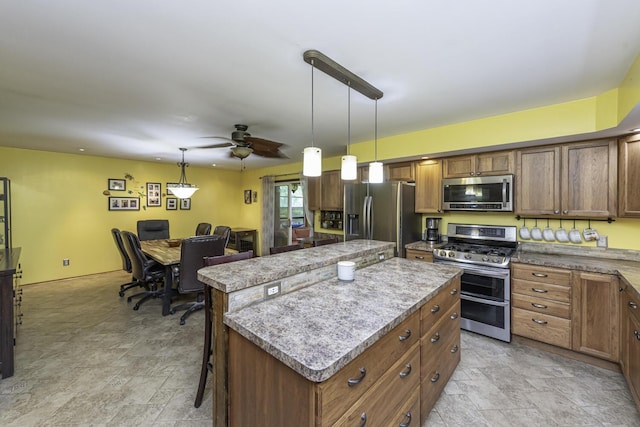 7715 Marquis Dr, Dexter, MI 48130 - kitchen featuring appliances with stainless steel finishes, a kitchen island, stone finish floors, and decorative light fixtures