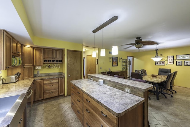7715 Marquis Dr, Dexter, MI 48130 - kitchen featuring stone tile floors, a center island, ceiling fan, and brown cabinets