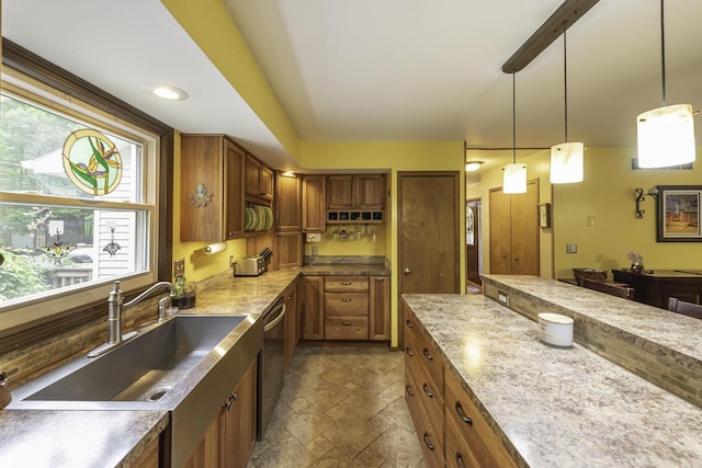 7715 Marquis Dr, Dexter, MI 48130 - kitchen featuring brown cabinetry, stone tile flooring, stainless steel dishwasher, and decorative light fixtures