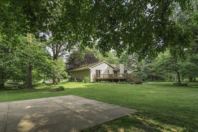 7715 Marquis Dr, Dexter, MI 48130 - view of grassy yard featuring a wooden deck, a patio, and view of wooded area