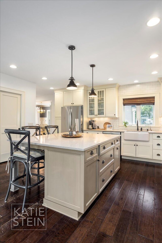 859 Orchard Ave SE, East Grand Rapids, MI 49506 - kitchen with freestanding refrigerator, a center island, a kitchen breakfast bar, dark wood-style flooring, and decorative light fixtures