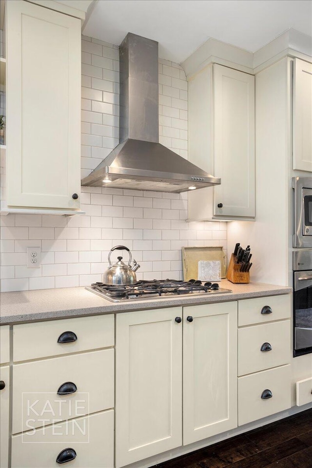 859 Orchard Ave SE, East Grand Rapids, MI 49506 - kitchen featuring wall chimney exhaust hood, appliances with stainless steel finishes, tasteful backsplash, and white cabinets