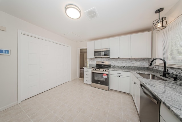 25255 Orchard Grove St, Southfield, MI 48033 - kitchen featuring stainless steel appliances, tasteful backsplash, white cabinetry, light stone counters, and decorative light fixtures