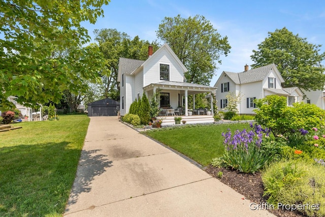 339 W Main Ave, Zeeland, MI 49464 - view of front facade with covered porch, a front yard, a detached garage, and a chimney