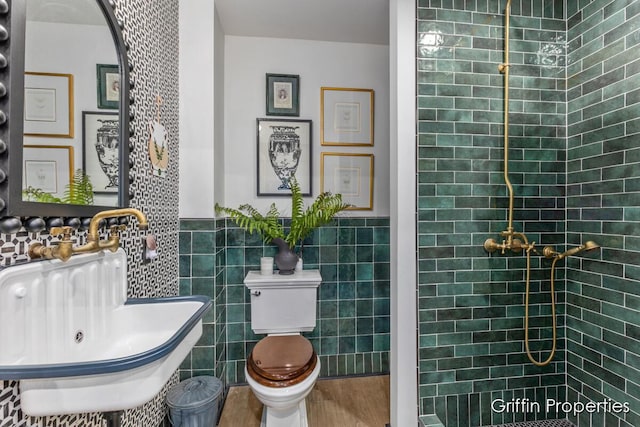 339 W Main Ave, Zeeland, MI 49464 - bathroom with tile walls, wood finished floors, a tile shower, and wainscoting
