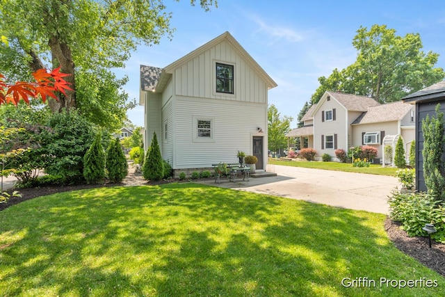 339 W Main Ave, Zeeland, MI 49464 - rear view of house featuring board and batten siding, a lawn, and a patio area