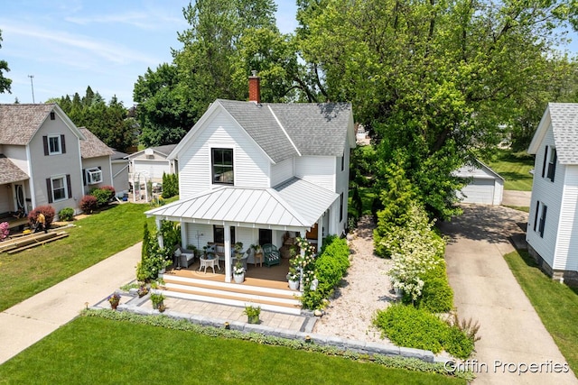 339 W Main Ave, Zeeland, MI 49464 - view of front facade with a porch, a standing seam roof, an outbuilding, a front lawn, and a chimney