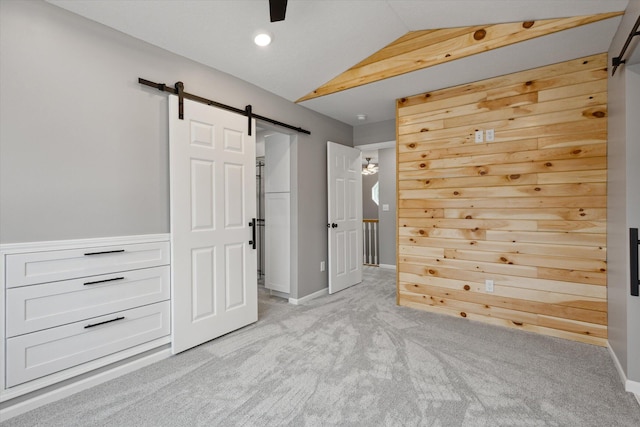 313 E Main St, Marion, MI 49665 - unfurnished bedroom with a barn door, light carpet, lofted ceiling, and recessed lighting