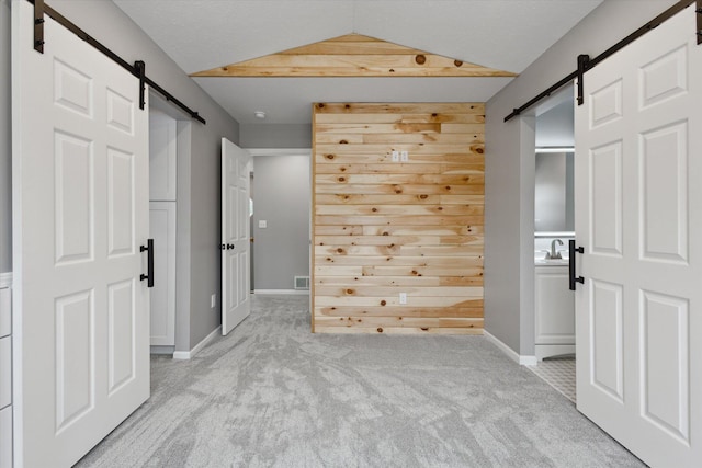 313 E Main St, Marion, MI 49665 - unfurnished bedroom featuring a barn door, vaulted ceiling, carpet flooring, and ensuite bathroom