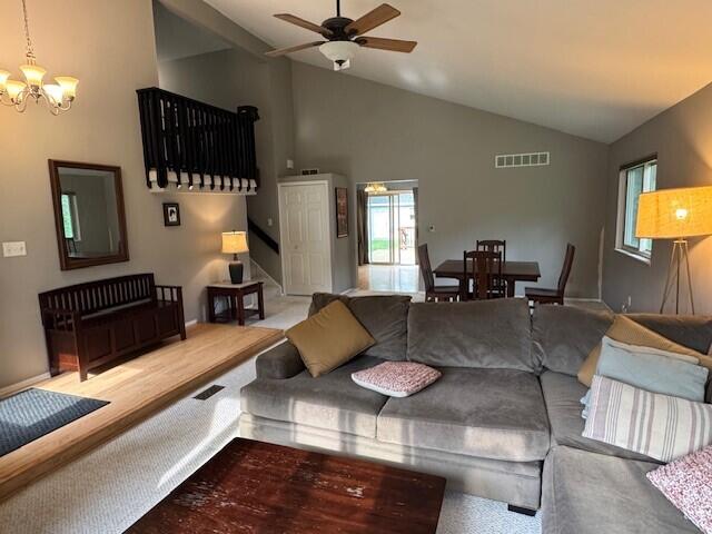 5689 Rothbury Ct, Ypsilanti, MI 48197 - carpeted living area featuring a chandelier, ceiling fan, stairs, and high vaulted ceiling