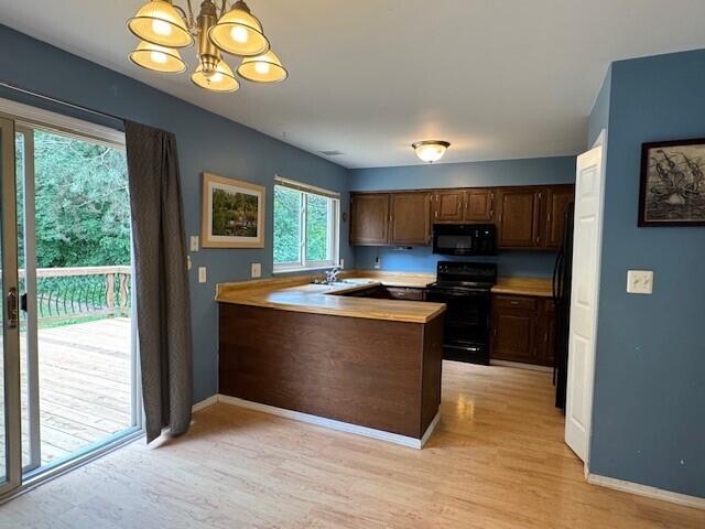 5689 Rothbury Ct, Ypsilanti, MI 48197 - kitchen with black appliances, a chandelier, light wood-style flooring, light countertops, and a peninsula