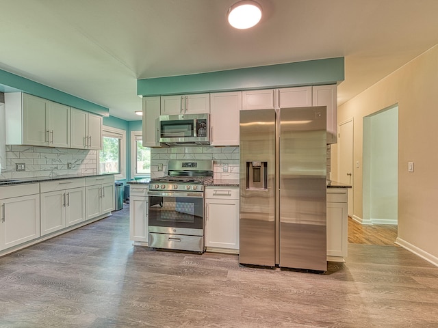219 Park St, Tecumseh, MI 49286 - kitchen with stainless steel appliances, backsplash, light wood-style floors, and dark countertops