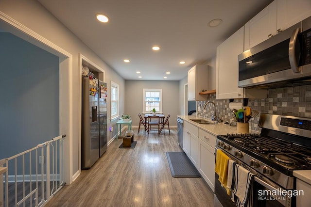 5161 Grand River Dr NE, Grand Rapids, MI 49525 - kitchen with stainless steel appliances, white cabinetry, decorative backsplash, light wood-type flooring, and recessed lighting